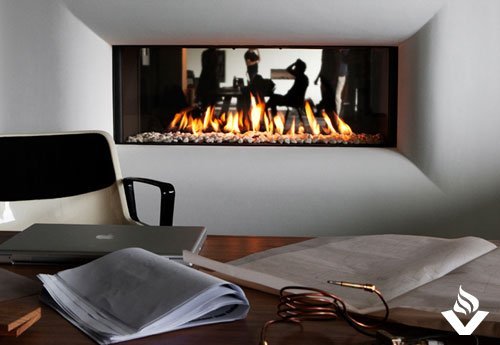 A landscape fireplace lies in the background of an office desk setup