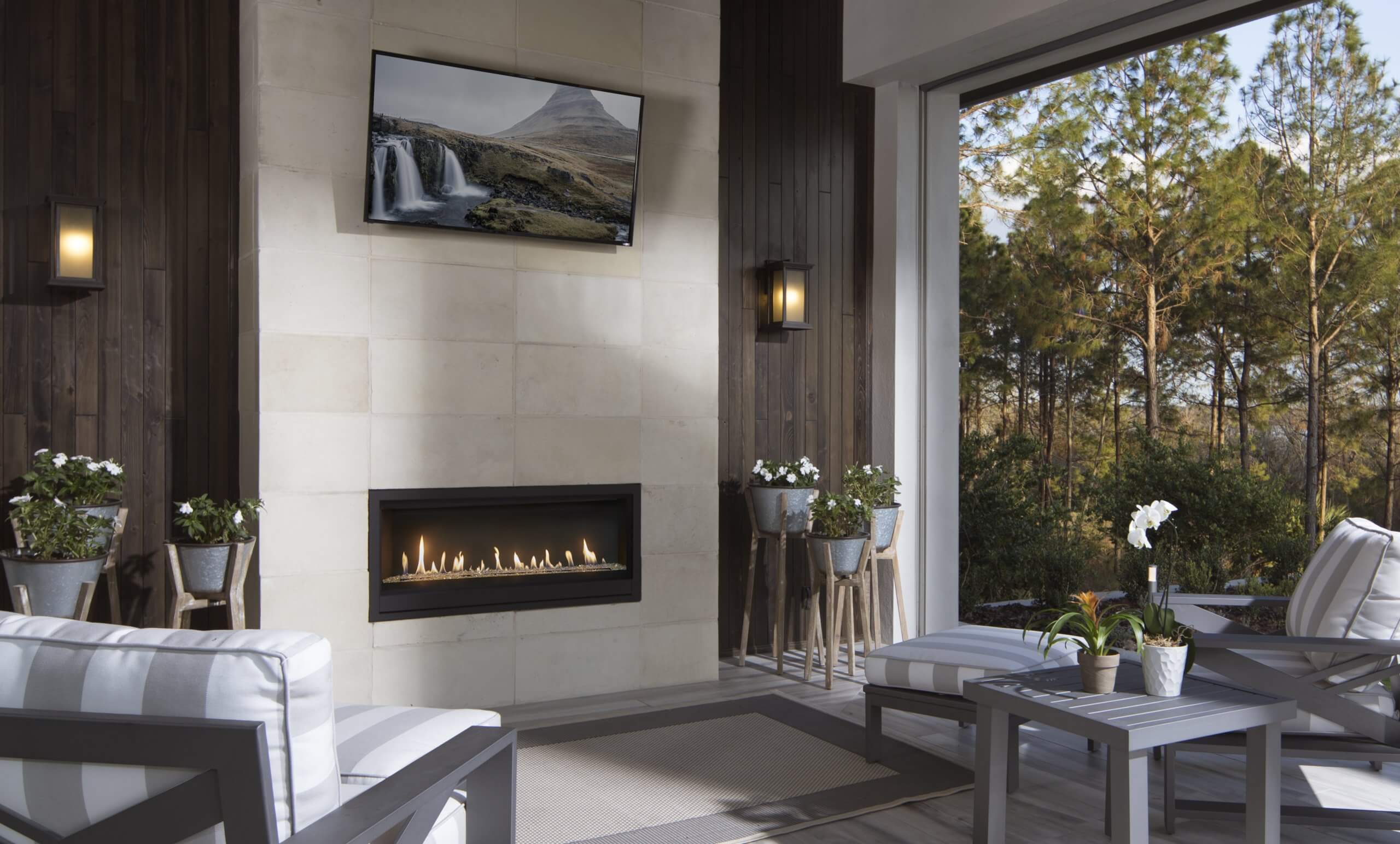 Outdoor room equipped with linear gas fireplace and TV above